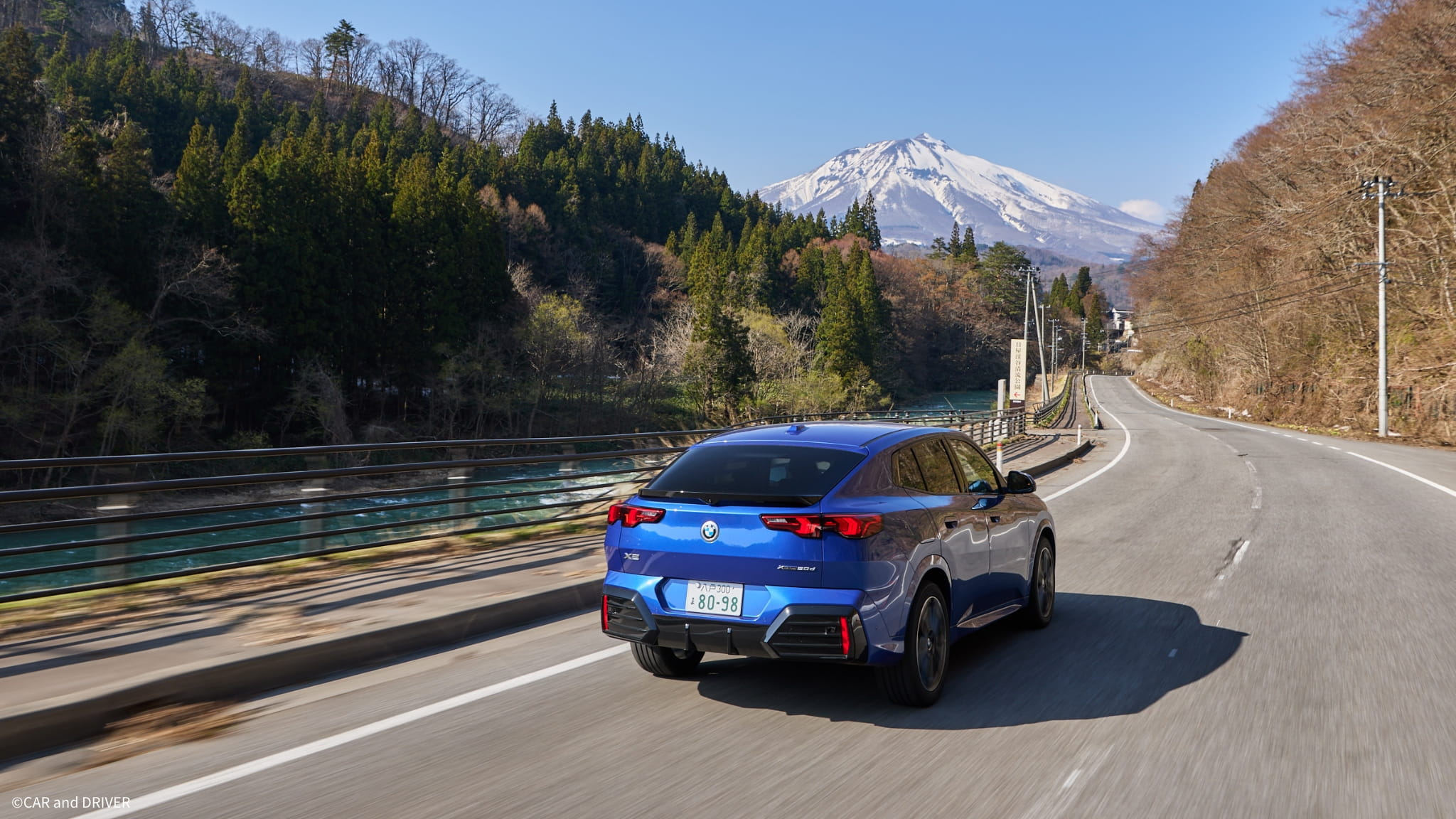 岩木山が遠くに見える道を進む自動車